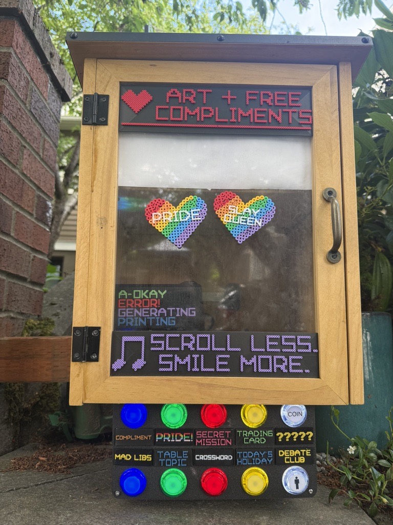 A wooden Joy Machine with arcade buttons and pixel art signs reading art and free compliments.